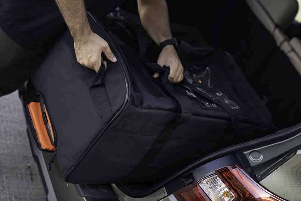 The Black Buffalo Duffel shown being loaded into the back of a vehicle with the top handles and pull handles.
