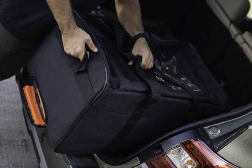 The Black Buffalo Duffel shown being loaded into the back of a vehicle with the top handles and pull handles.
