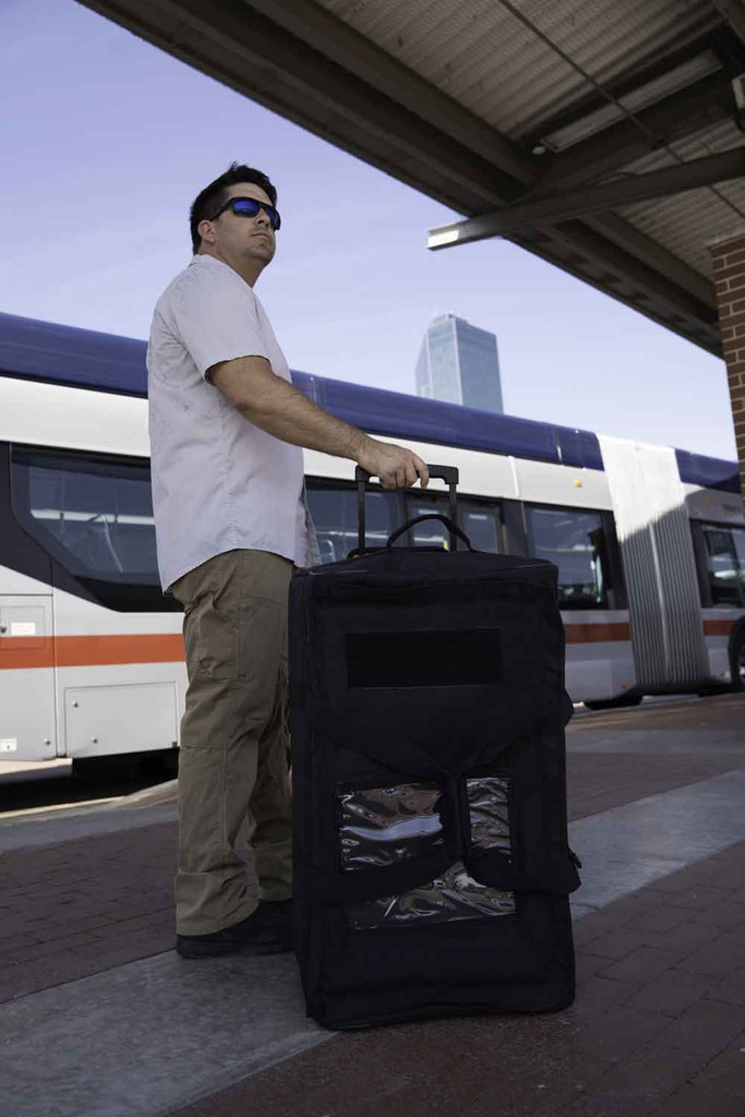 Black Buffalo Duffel shown upright being towed at bus stop.