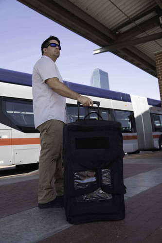 Black Buffalo Duffel shown upright being towed at bus stop.