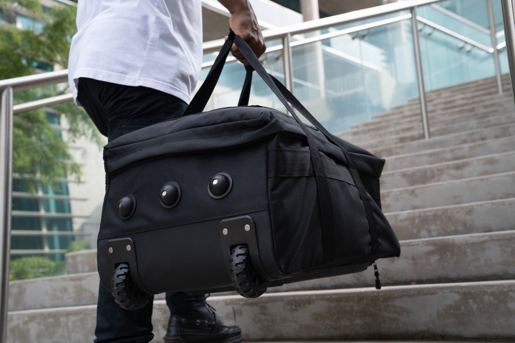Mini Buffalo Rolling Duffel in Black carried as duffel showing the bottom side with three feet and two wheels.