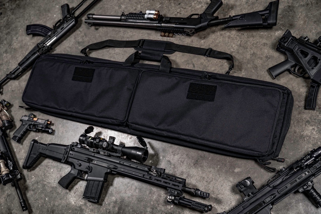 Black Single Rifle Case on concrete floor with firearms around it.