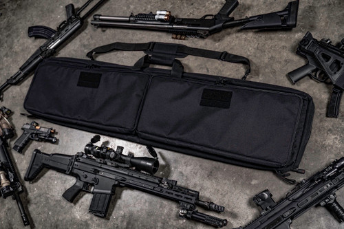Black Single Rifle Case on concrete floor with firearms around it.
