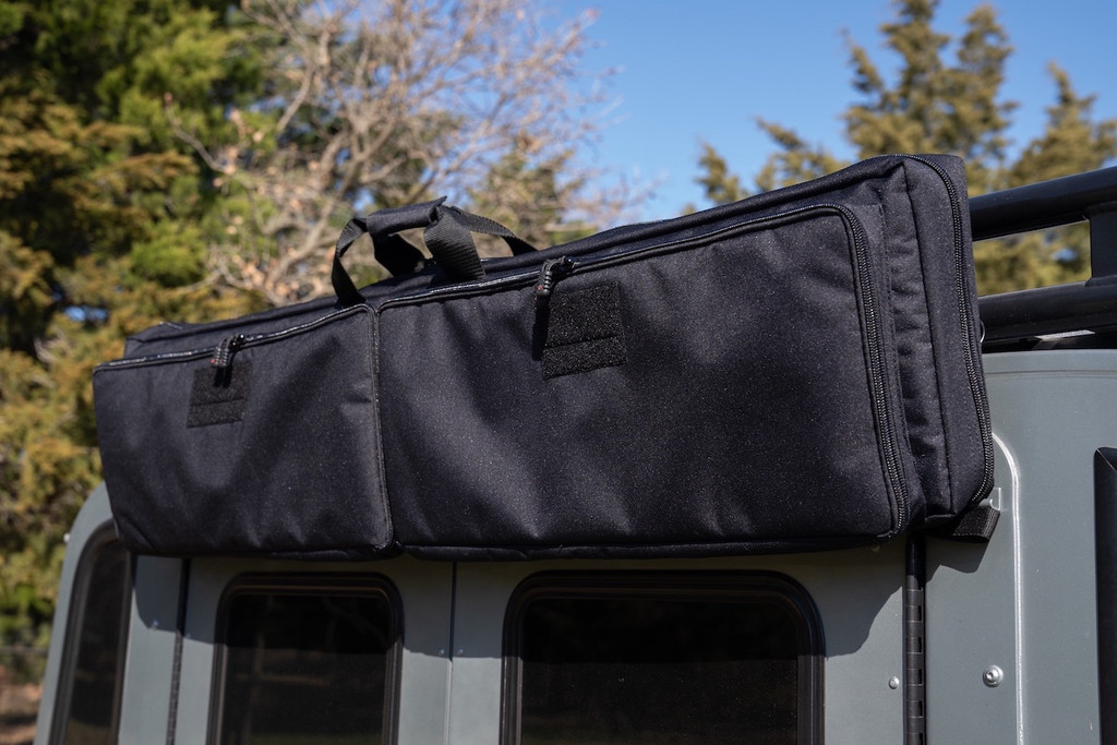 Black Single Rifle Case attached to top of grey sports utility vehicle.