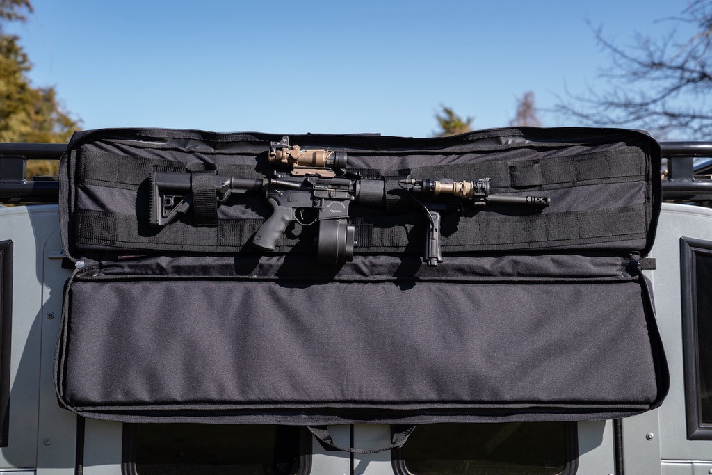 Black Single Rifle Case attached to top of grey sports utility vehicle opened with firearm secured inside.