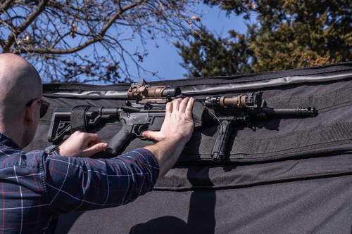 Firearm being removed from Single Rifle Case attached to top of grey sports utility vehicle.
