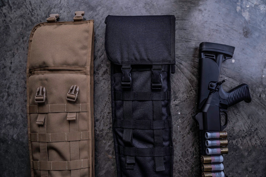 The tops of two coyote brown and black Shotgun Scabbards on a grey surface next to a black firearm with ammunition.