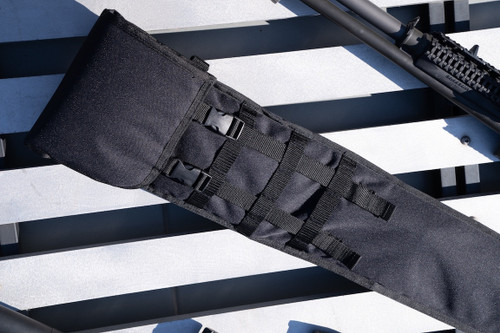 The top of a Black Shotgun Scabbard on a white slat surface next to a firearm.