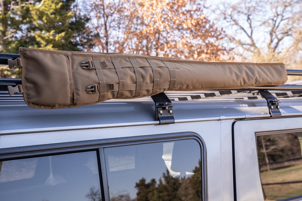 Coyote brown Shotgun Scabbard on racks attached to top of grey sports utility vehicle.