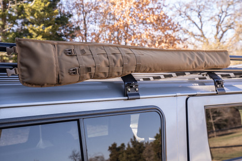 Coyote brown Shotgun Scabbard on racks attached to top of grey sports utility vehicle.