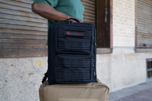 Front of black Midland Backpack sitting on top of coyote brown Mini Buffalo Rolling Duffel.